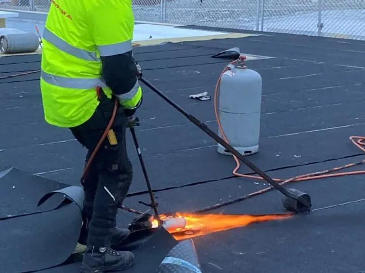 Takläggare svetsar takpapp med gasol på ett platt tak