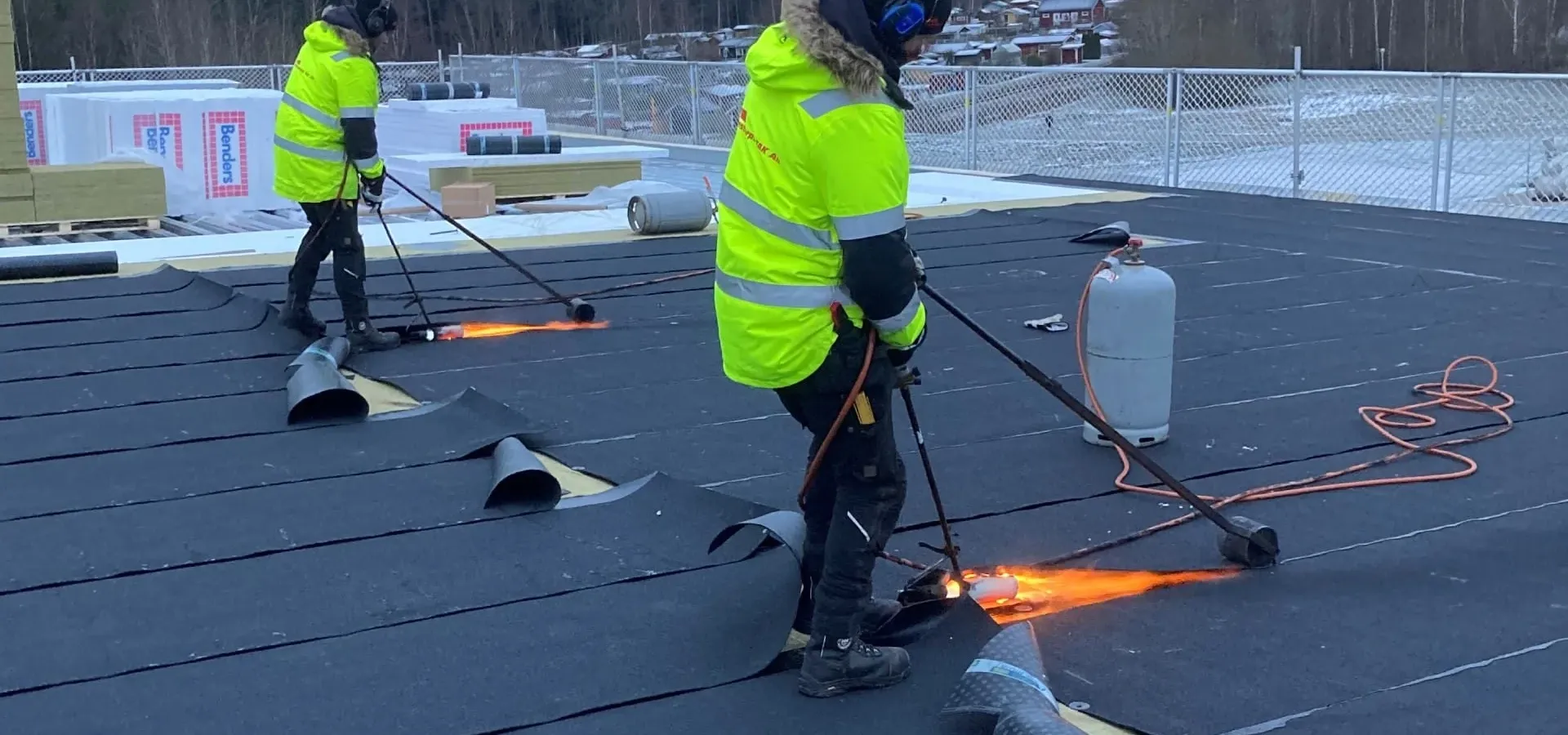 Två takläggare från Stenstorps Tak svetsar takpapp på ett platt tak
