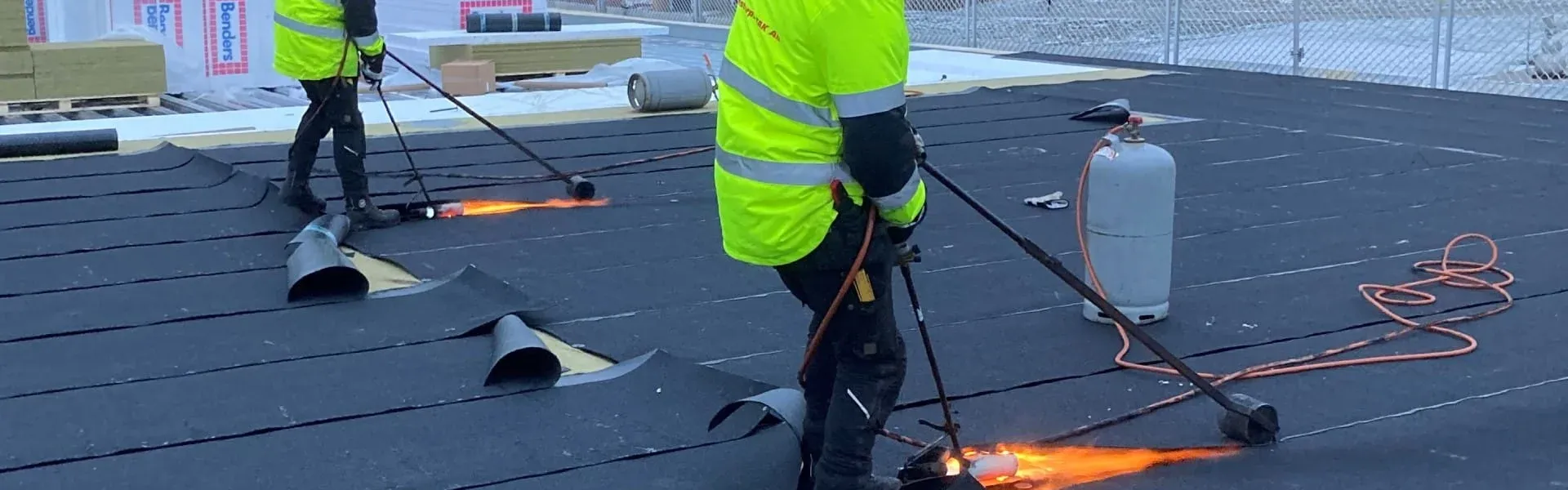 Två takläggare från Stenstorps Tak svetsar takpapp på ett platt tak
