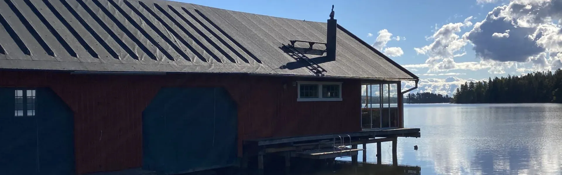 Röd sjöbod vid vattnet med nytt platt tak